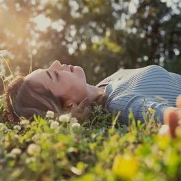 Frau liegt entspannt im Gras bei Sonnenlicht