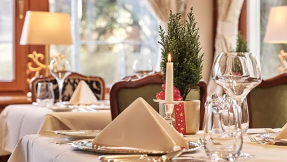 Eleganter eingedeckter Tisch mit Kerze und Weihnachtsdeko in Restaurant