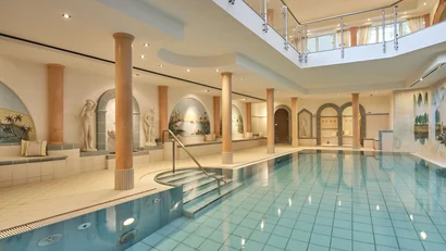 Großes Hallenbad mit Säulen und Wandmalereien im Wellnessbereich