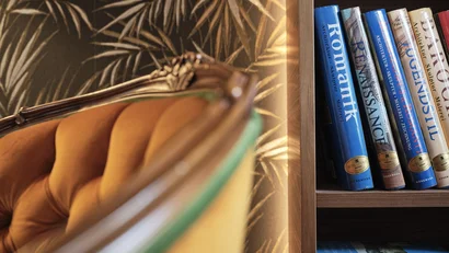 Nahaufnahme eines gelben Sessels neben einem Bücherregal mit Kunstbüchern
