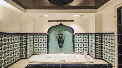 Whirlpool-Badewanne mit blau-weißen Kacheln und dekorativer Vase an der Wand