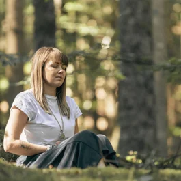 Frau meditiert entspannt im Wald sitzend mit geschlossenen Augen