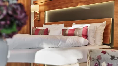Gemütliches Hotelzimmer mit bett, holzverkleidung und dekorativen kissen
